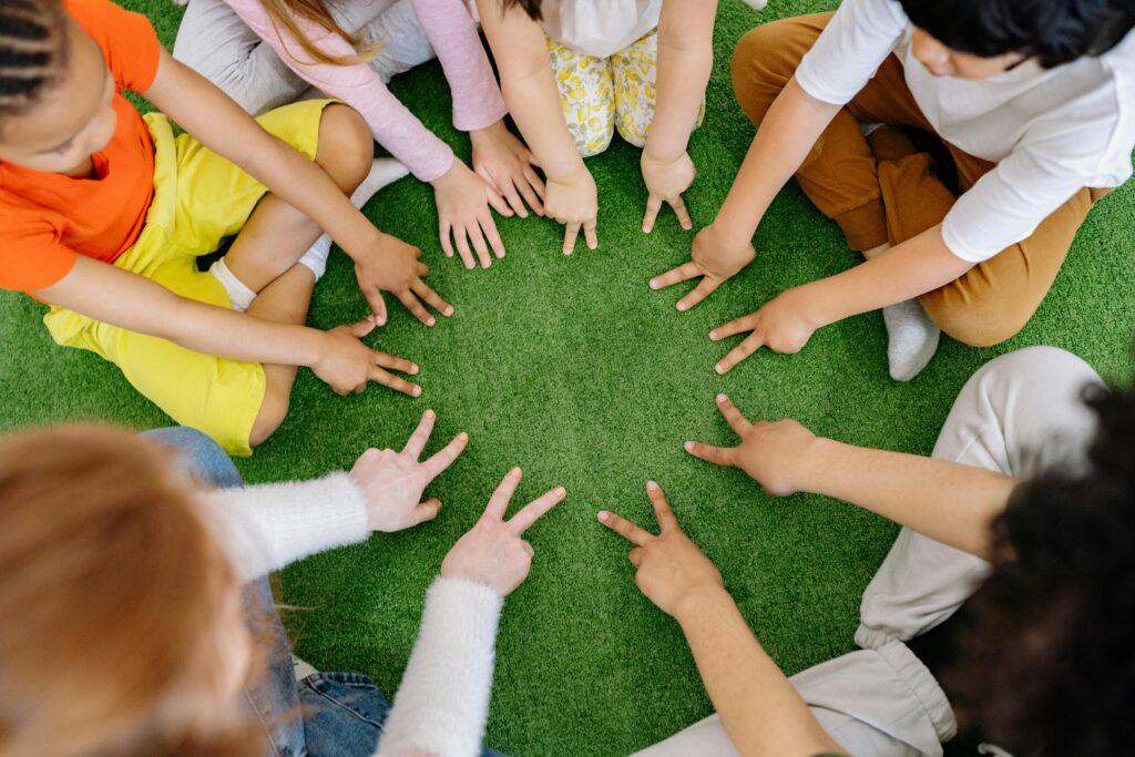 pexels-photo-8613319-8613319 Children sitting in a circle playing fun team games on artificial grass.